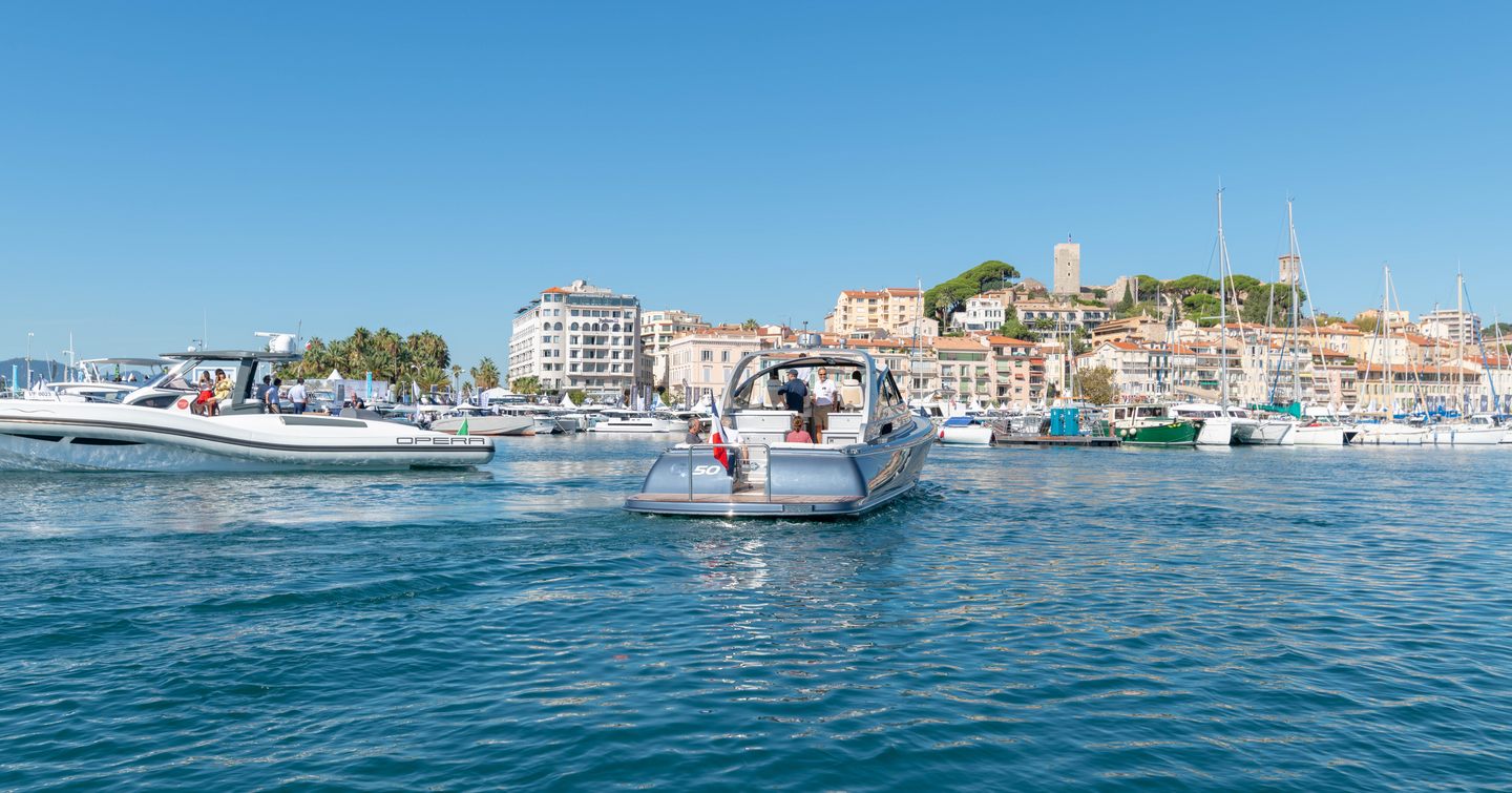 Overview of motor boats entering marina for CYF, surrounded by sea with Cannes in background