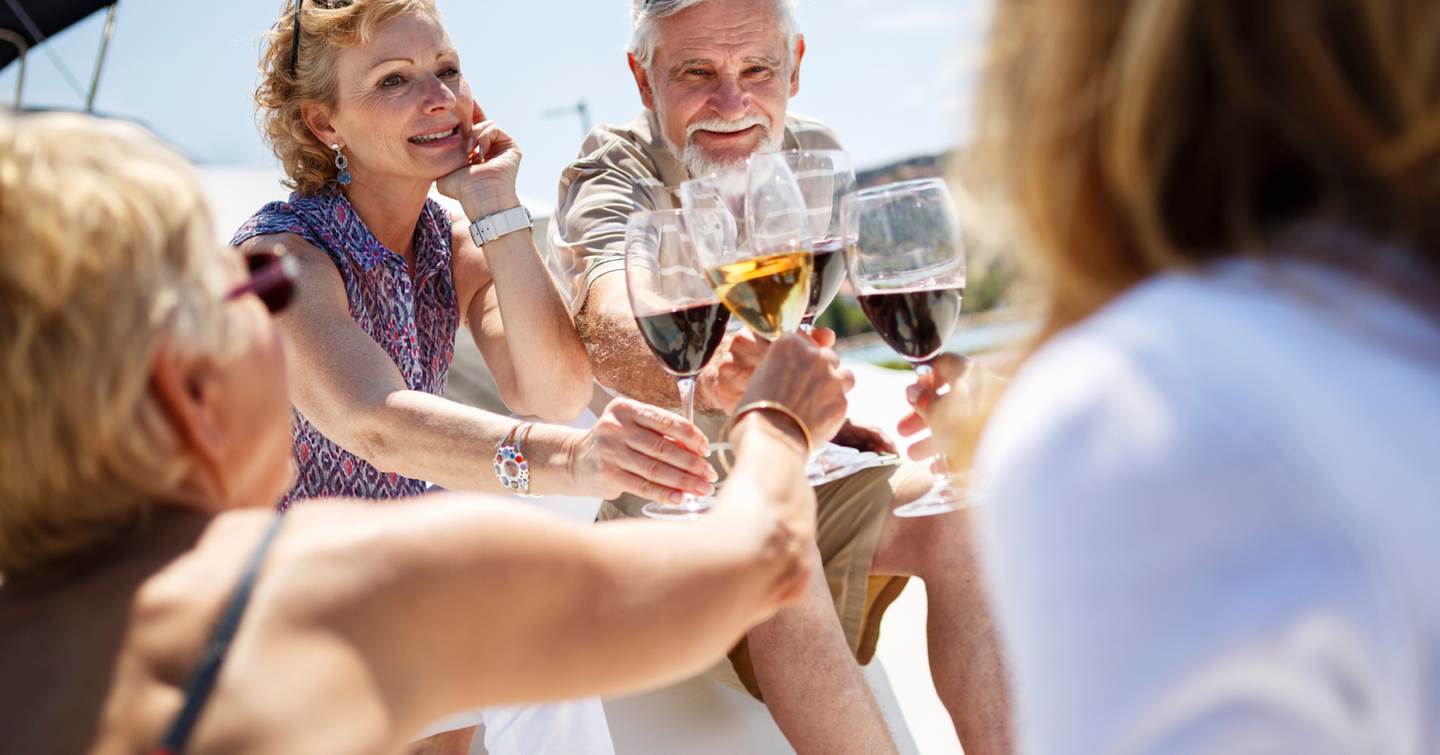 Senior friends toasting each other with wine on yacht