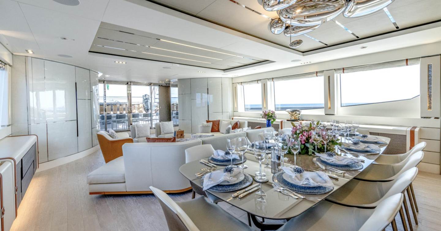 Superyacht Cabo main saloon with dining table and sofa