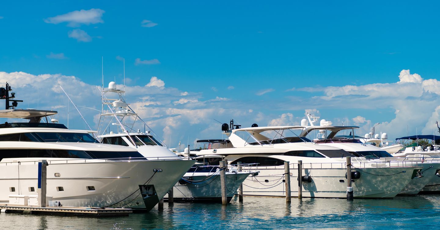 Motor yachts berthed in a line against a blue sky