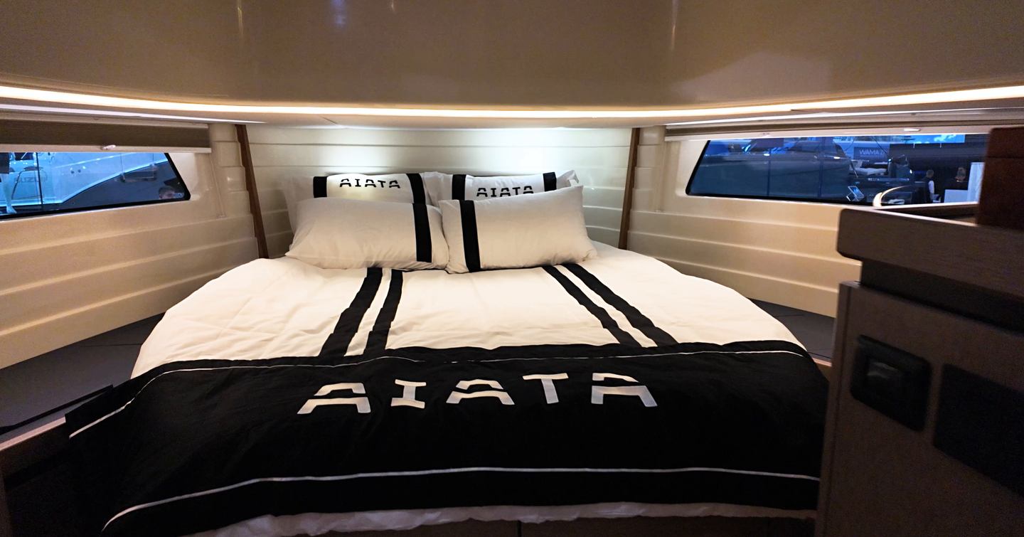 Forward cabin on the Aiata Sunfinder 50 with a large double berth, hull windows on both sides and overhead lighting.