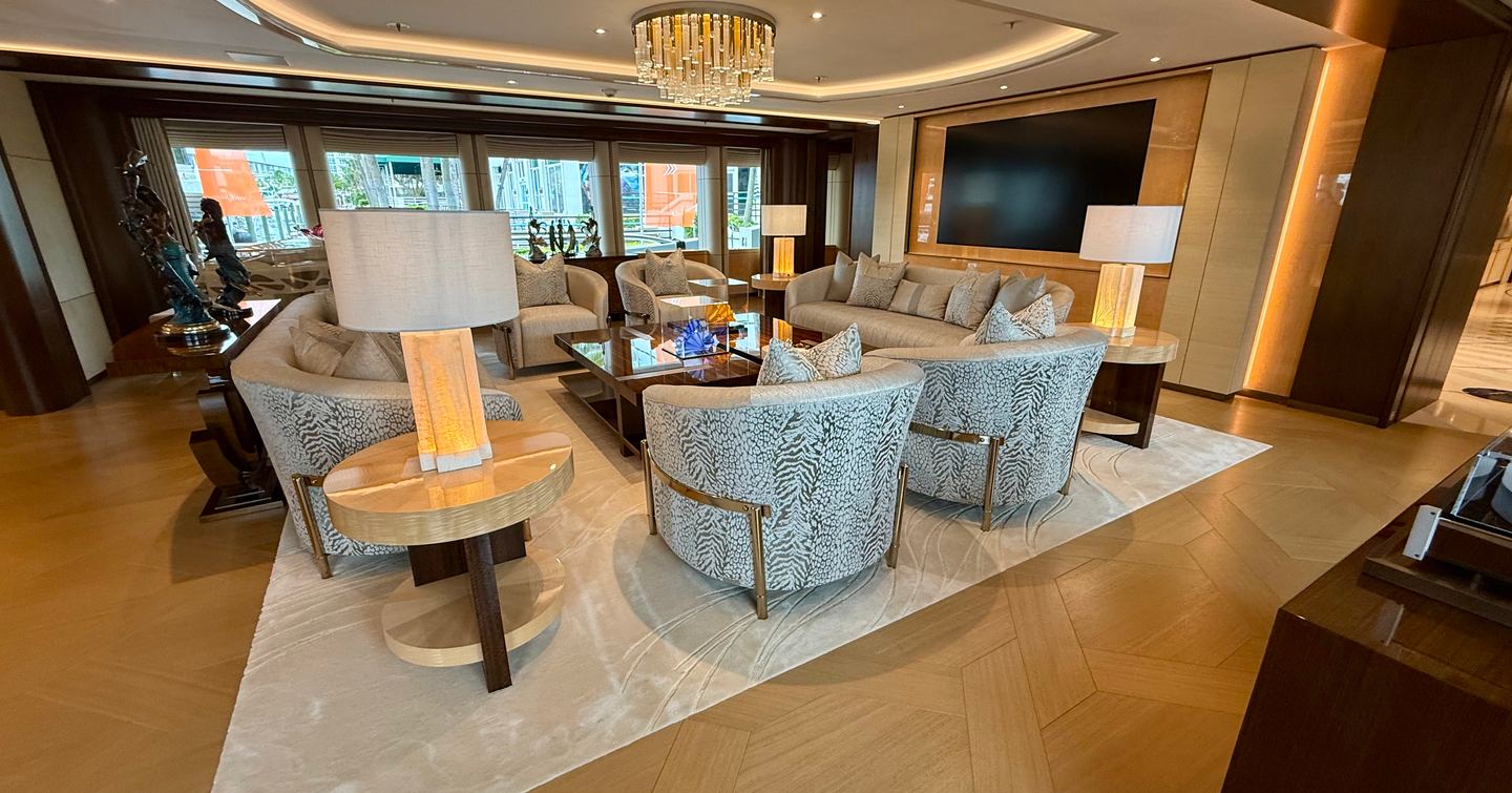Main saloon lounge seating area on the Amels 242 Casino Royale with large TV wall, sofas and chandelier lighting.