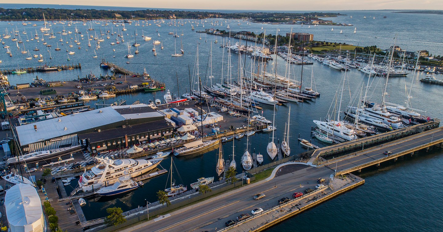 Elevated view of Safe Harbor Newport Shipyard, with multiple yachts moored, surrounded by sea