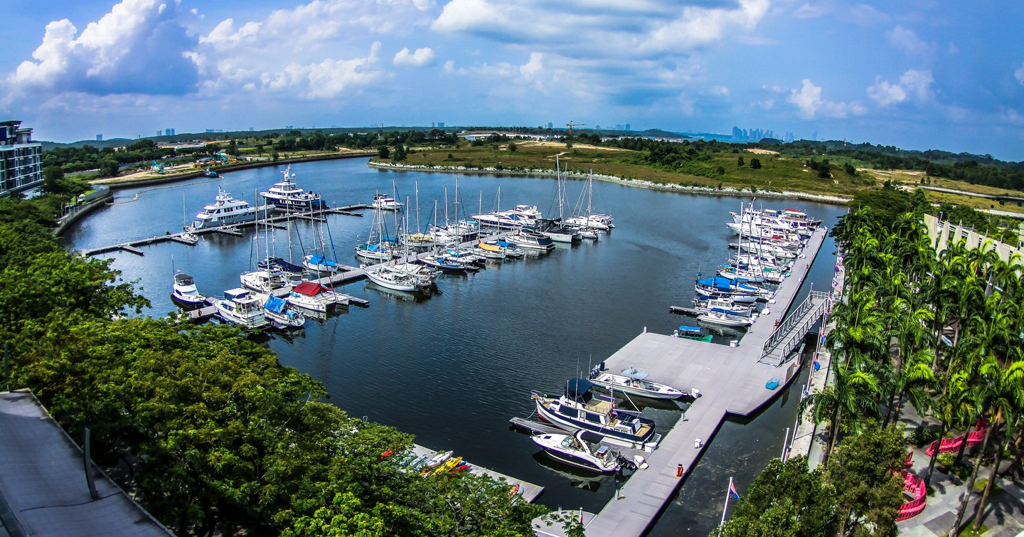 Overview of Puteri Harbour, Malaysia. Multiple boats berthed, surrounded by green foliage.