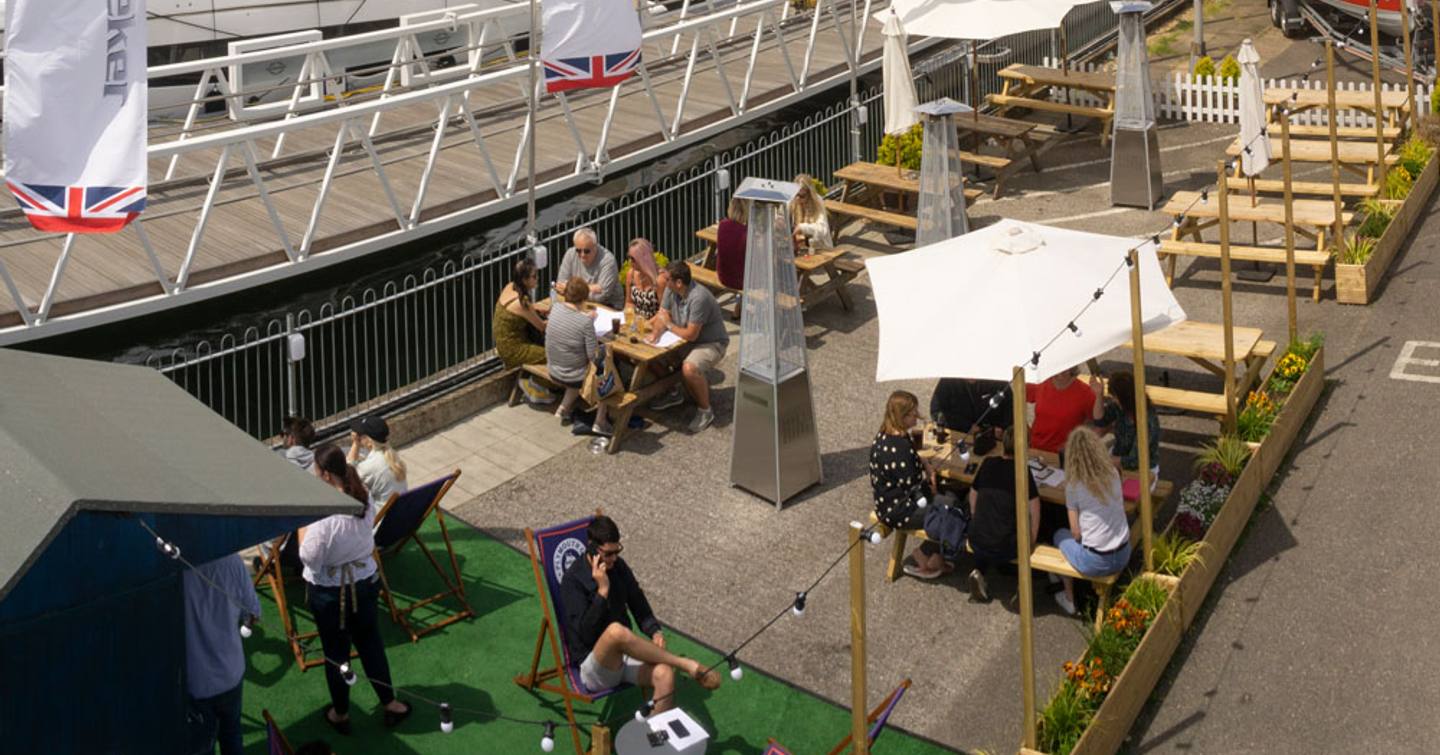 Eateries at Swanwick Marina, Southampton. Visitors to bost show sat at tables under parasols.