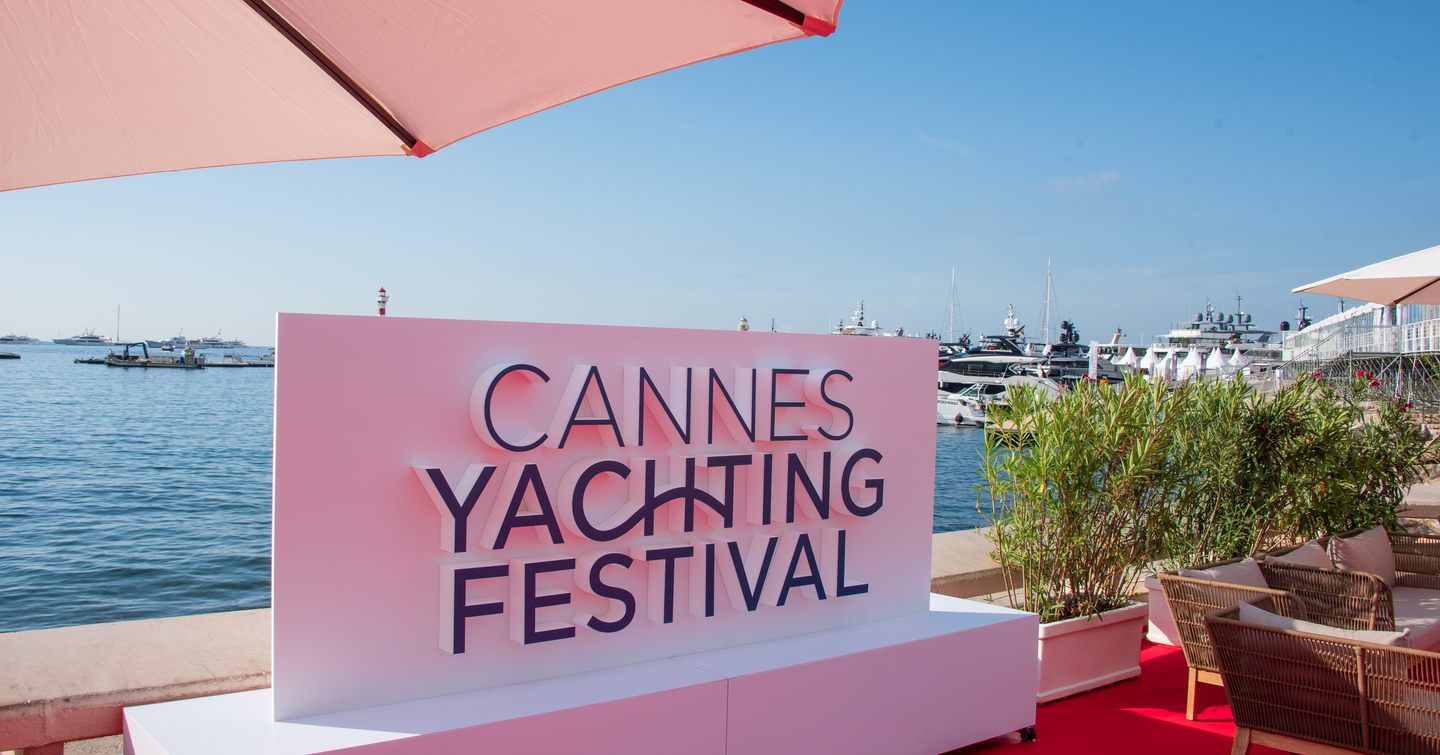 Overview of a sign reading Cannes Yachting Festival with the Bay of Cannes in the background