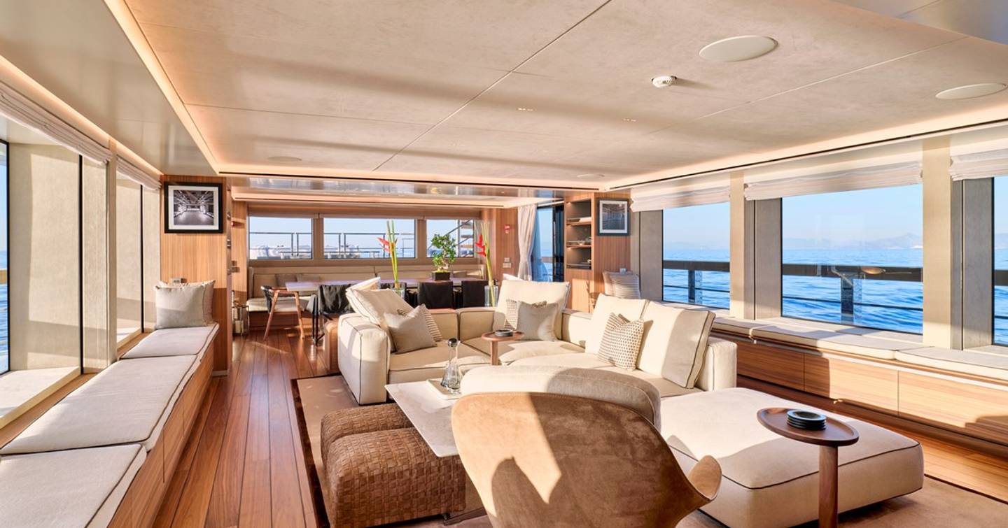 Superyacht Para Bellum main saloon with coffee tables, dining area and L-shaped sofa