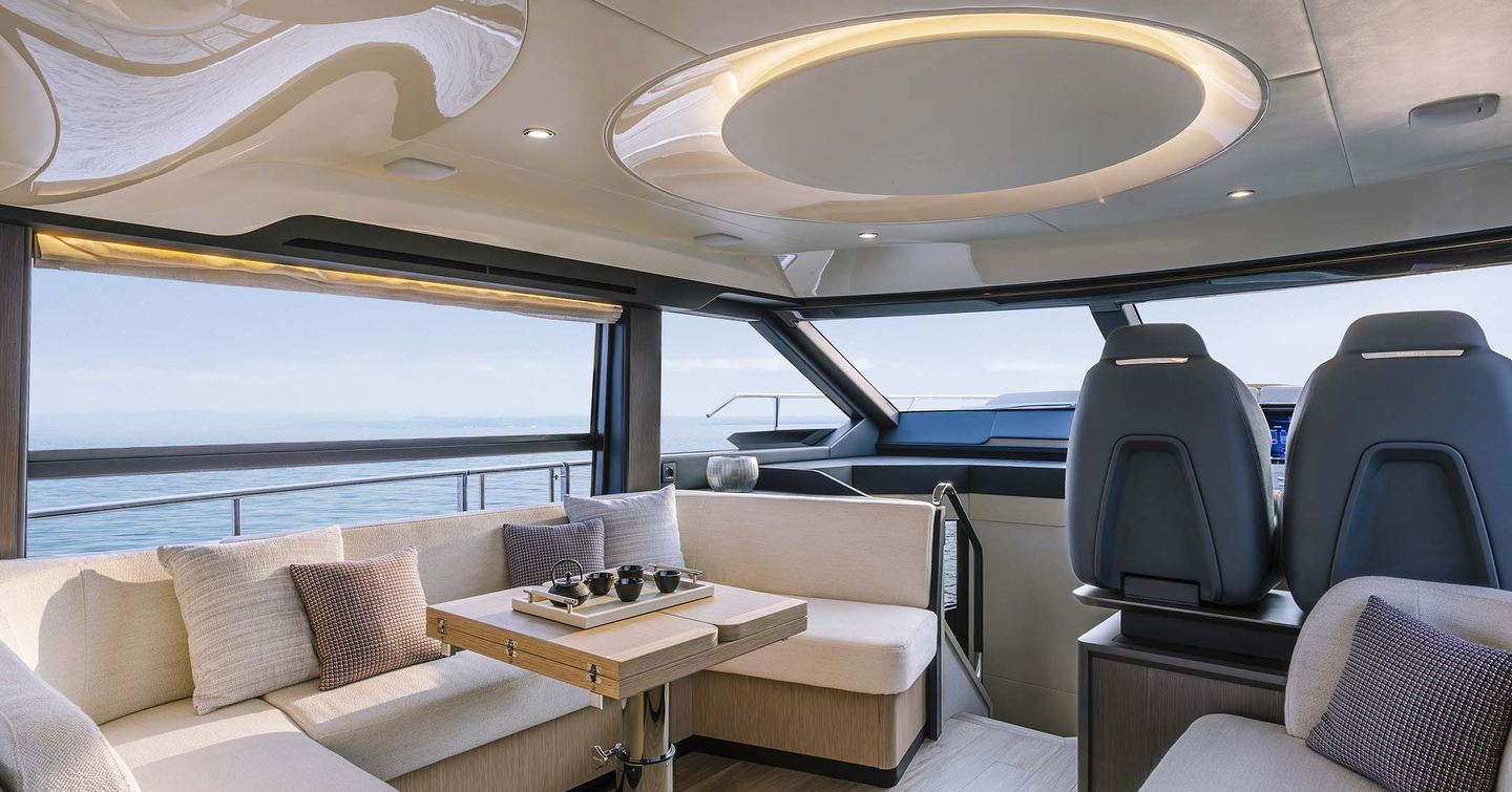 Next-Gen Absolute 52 FLY motor yacht interior with U-shaped white sofa and helm station