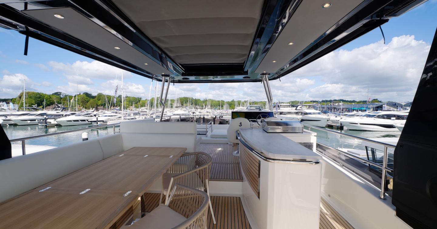 Beneteau Grand Trawler 63 flybridge with outdoor galley, dining area and helm station beneath the hardtop