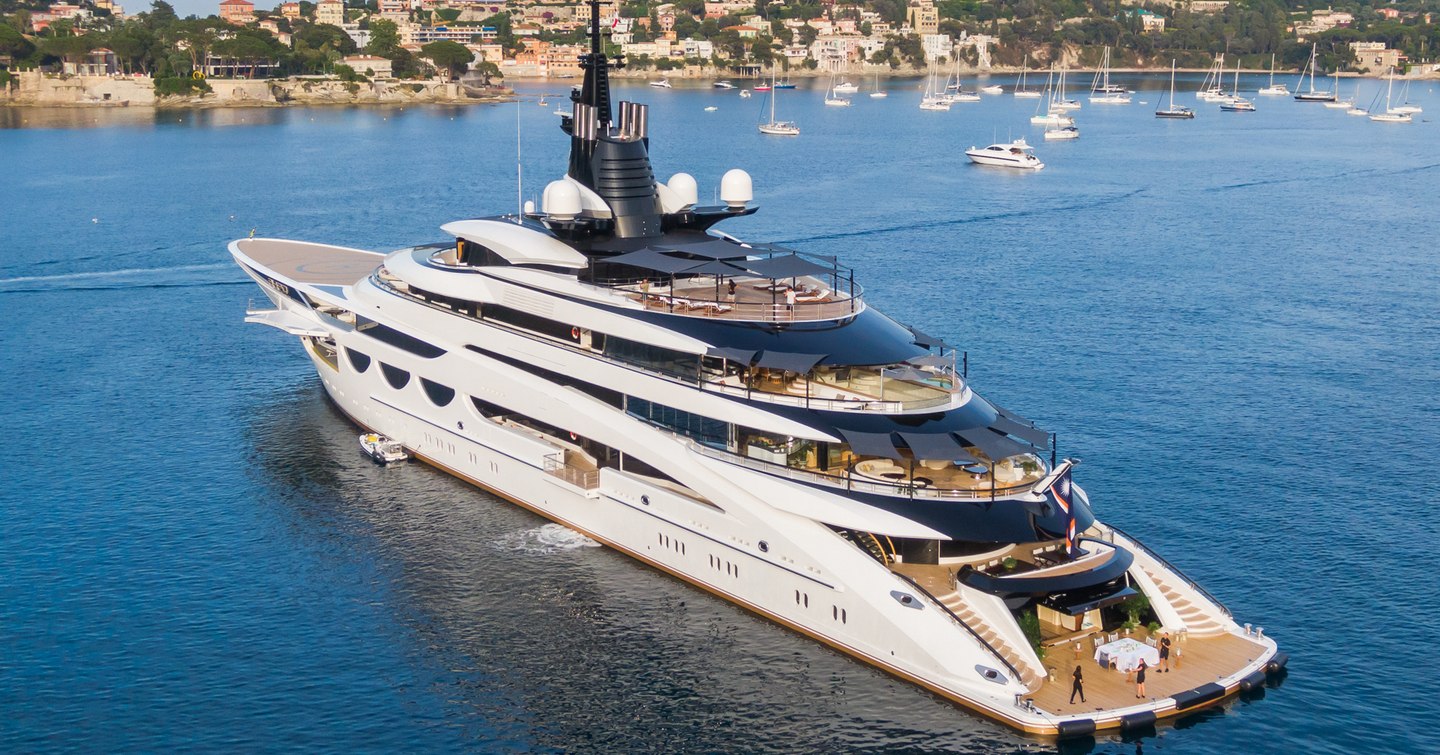 Aft decks onboard superyacht AHPO. Exterior furniture visible on all aft decks, the superyacht is surrounded by water at a Mediterranean bay.