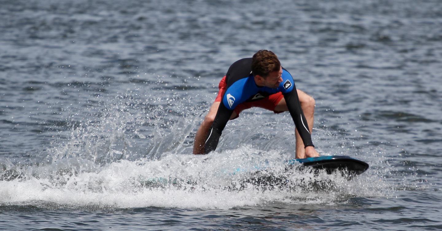 Man performing water sport demonstration on a paddle board, surrounded by sea