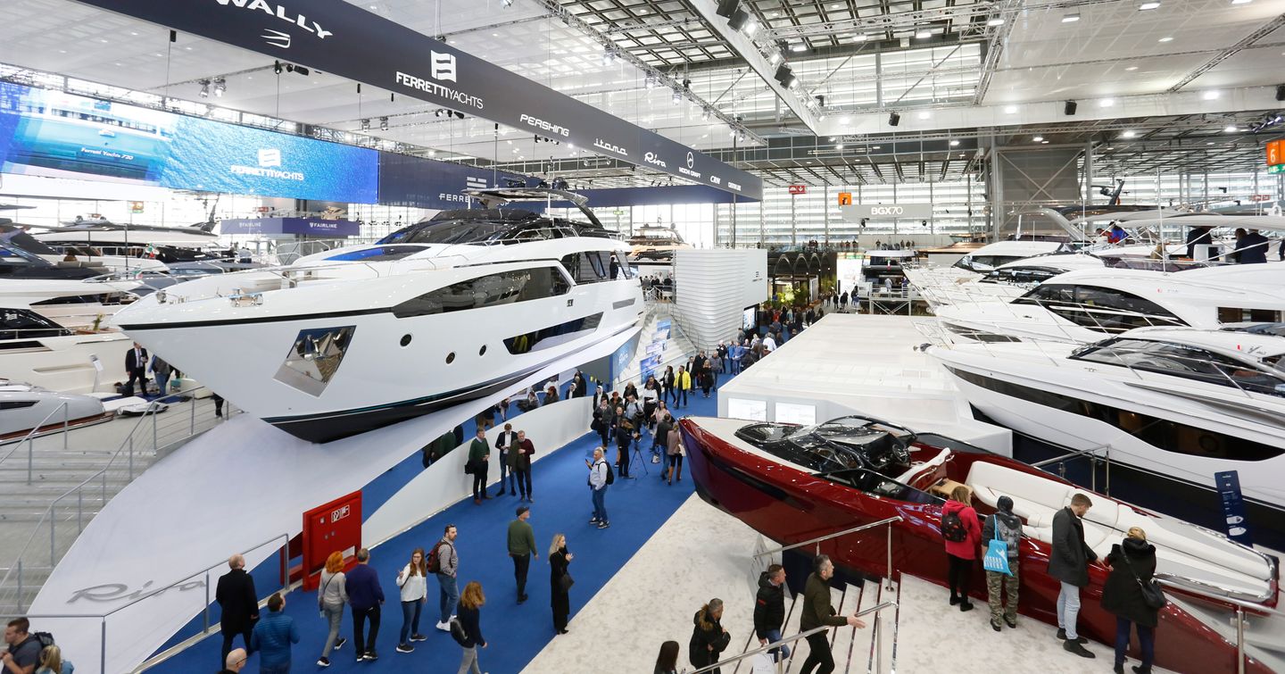 Yacht display at Boot Dusseldorf, many visitors walking around yachts on blue carpet.