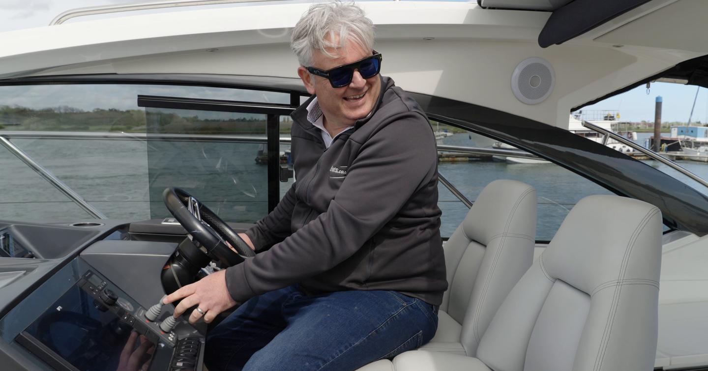 James Barke smiling at the helm of the Princess V39, using the controls during YachtBuyer's fuel-dock challenge.