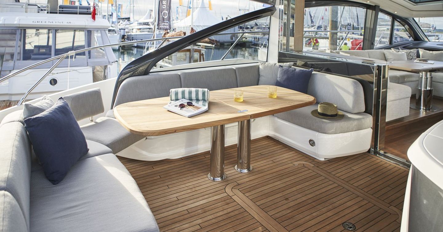 Princess V55 cockpit L-shaped seating and teak dining table beneath hardtop