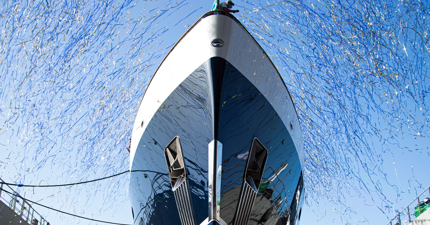 confetti flies over the top of Blue II yacht at its launch in a shot taken of the navy blue hull 