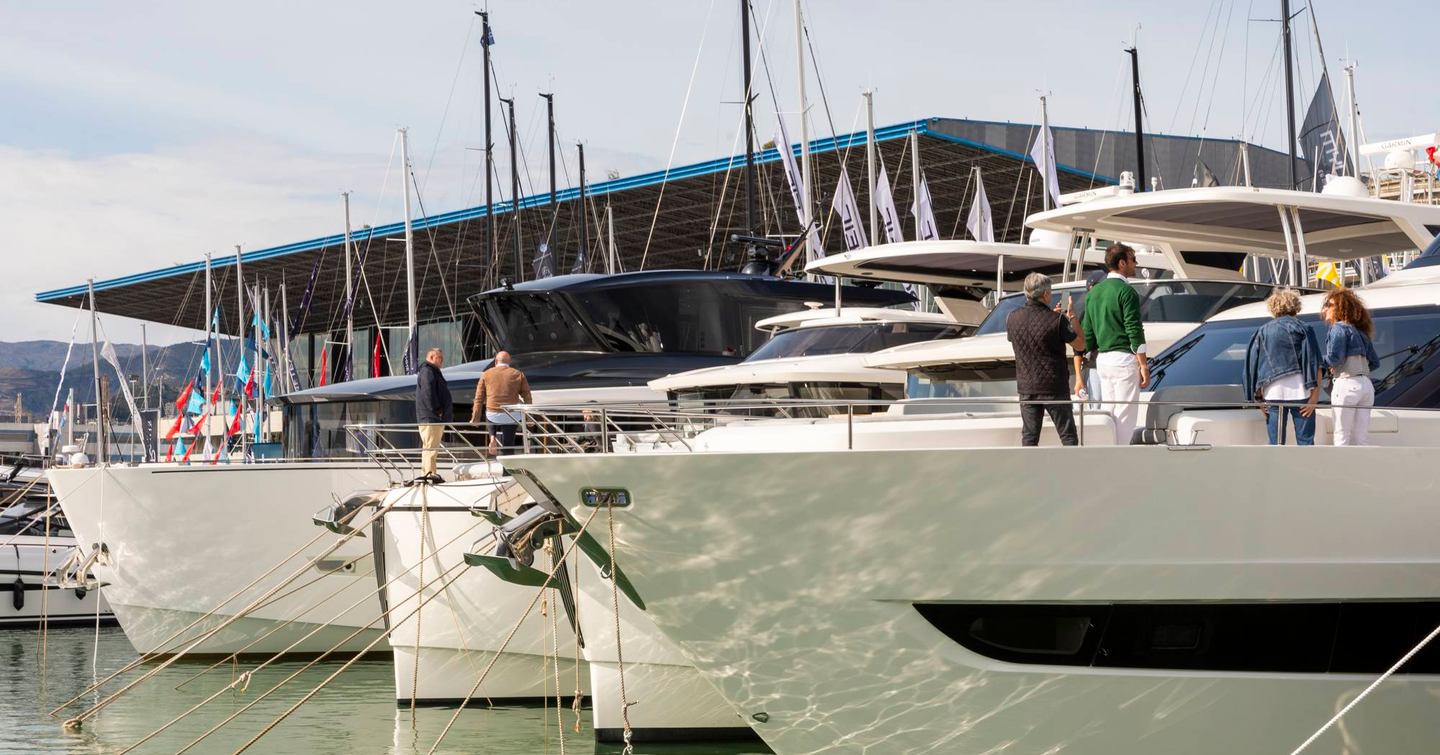 Yachts on show at Genoa International Boat Show, bows of boats moored against the building