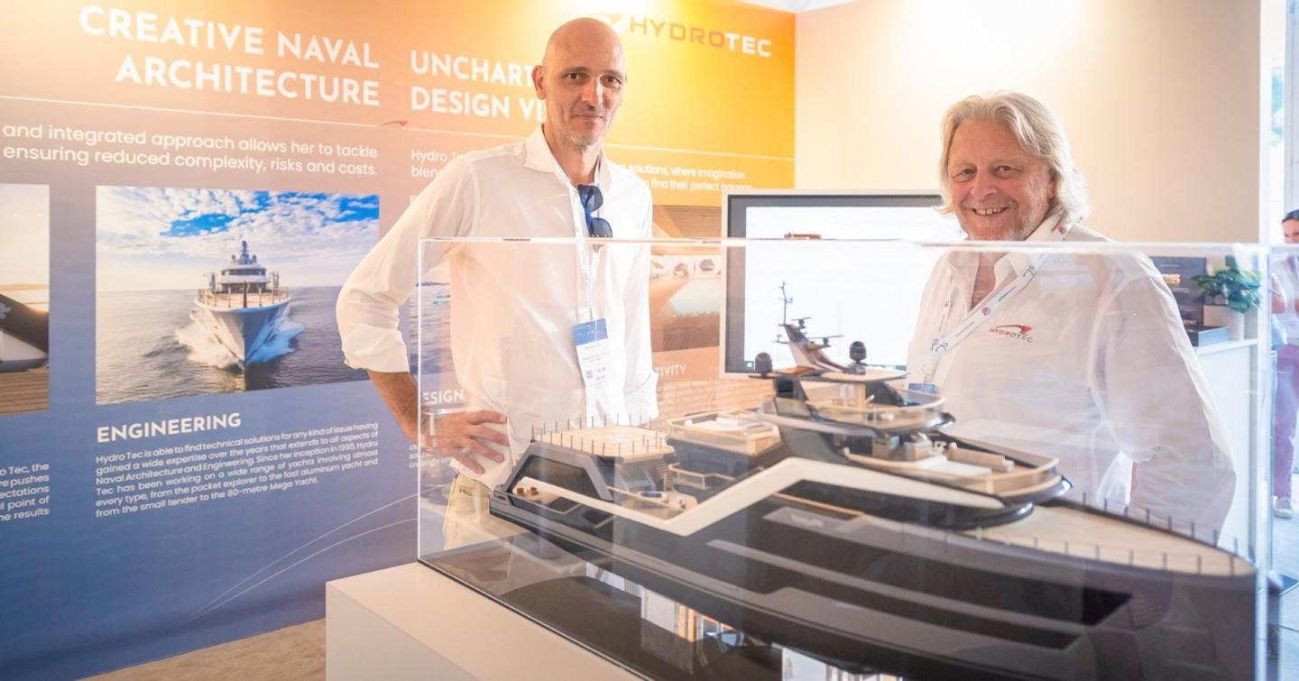 Two male exhibitors showcase a yacht model at the 2024 MYS Yacht Design & Innovation Hub