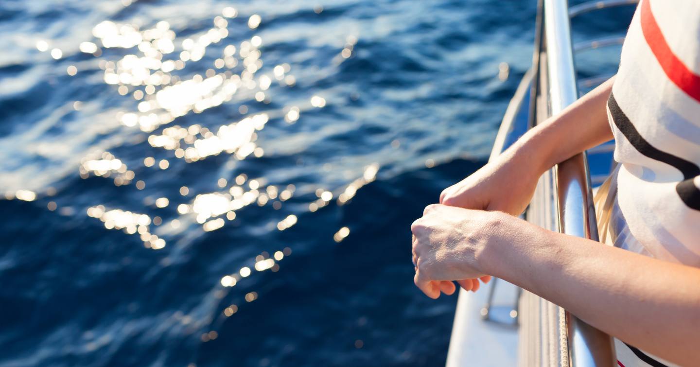 Woman leaning over handrails on a yacht 