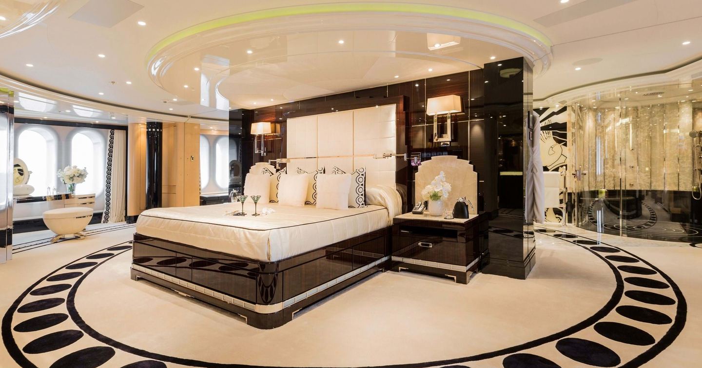 Lurssen yacht PHOENIX 2 owner's cabin with huge bed central in room with patterned bespoke carpet with black circles in circular ring around the bed area