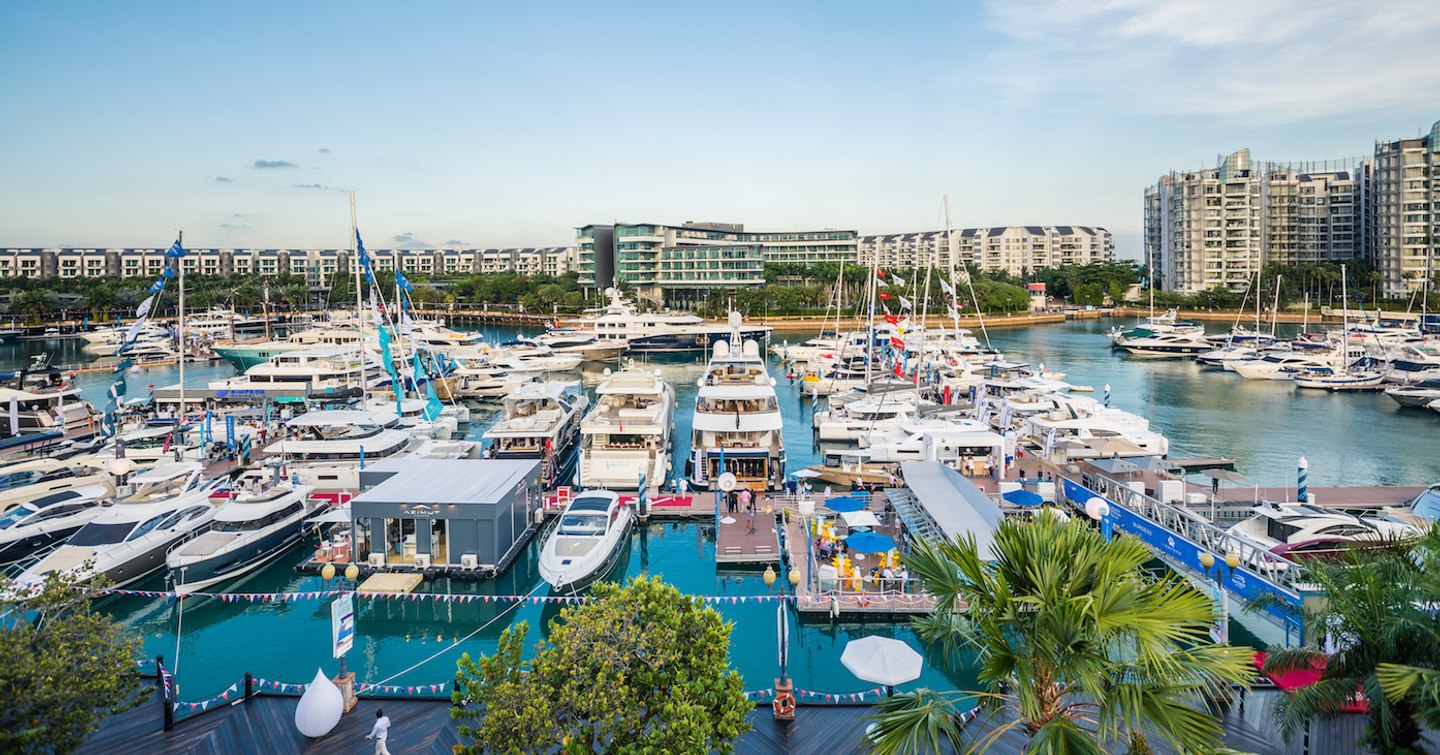 Overview of Sentosa Cove marina in Singapore. Lots of yachts berthed with hotels in the background.