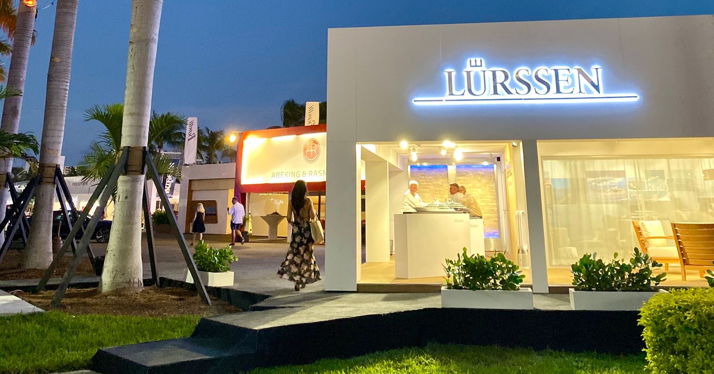 Lurssen logo lit up at night adjacent to palm trees