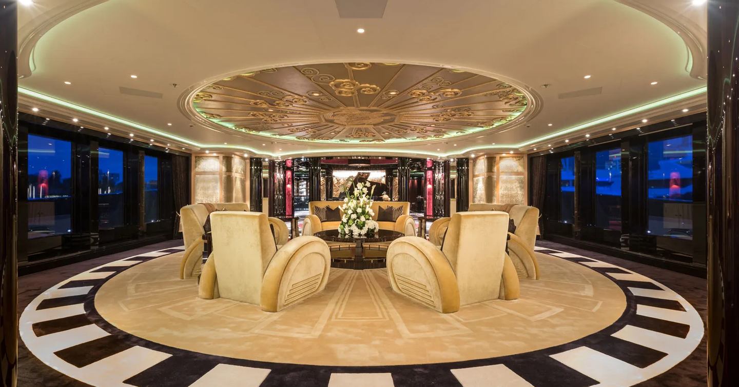 Lurssen yacht PHOENIX 2 circular interior room with black and white patterned flooring, massive ceiling feature, large stylistic chairs. shot taken at night as dark outside the large windows