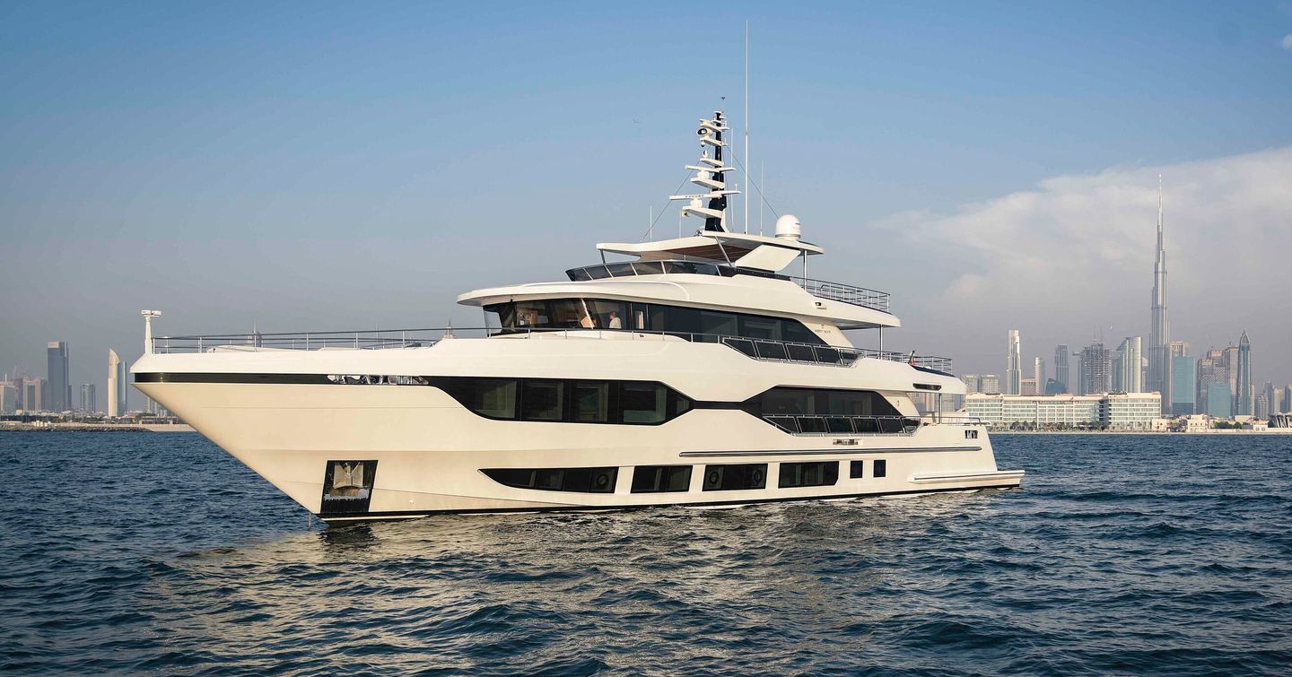 Side view of Majesty 120 exterior, underway with Dubai in background.