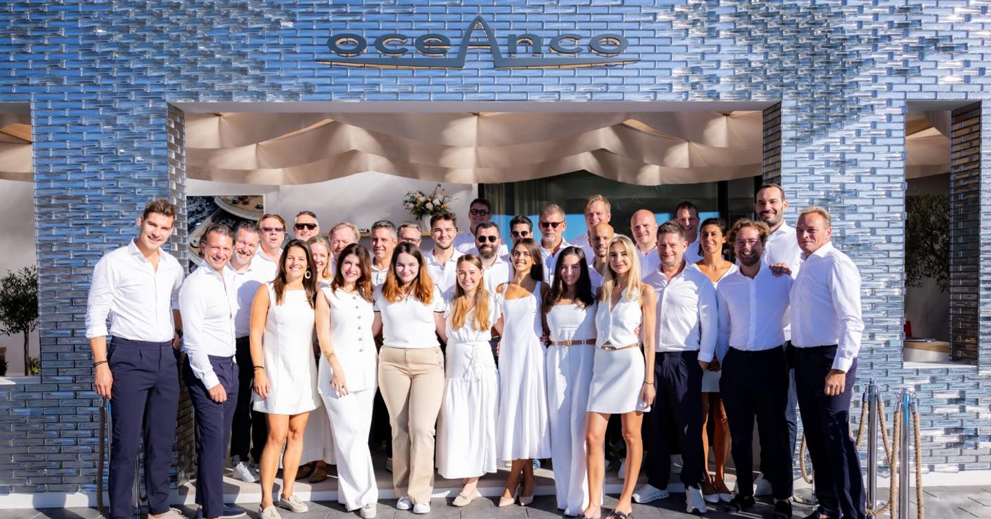 Oceanco team standing in from of Oceanco stand at Monaco Yacht Show