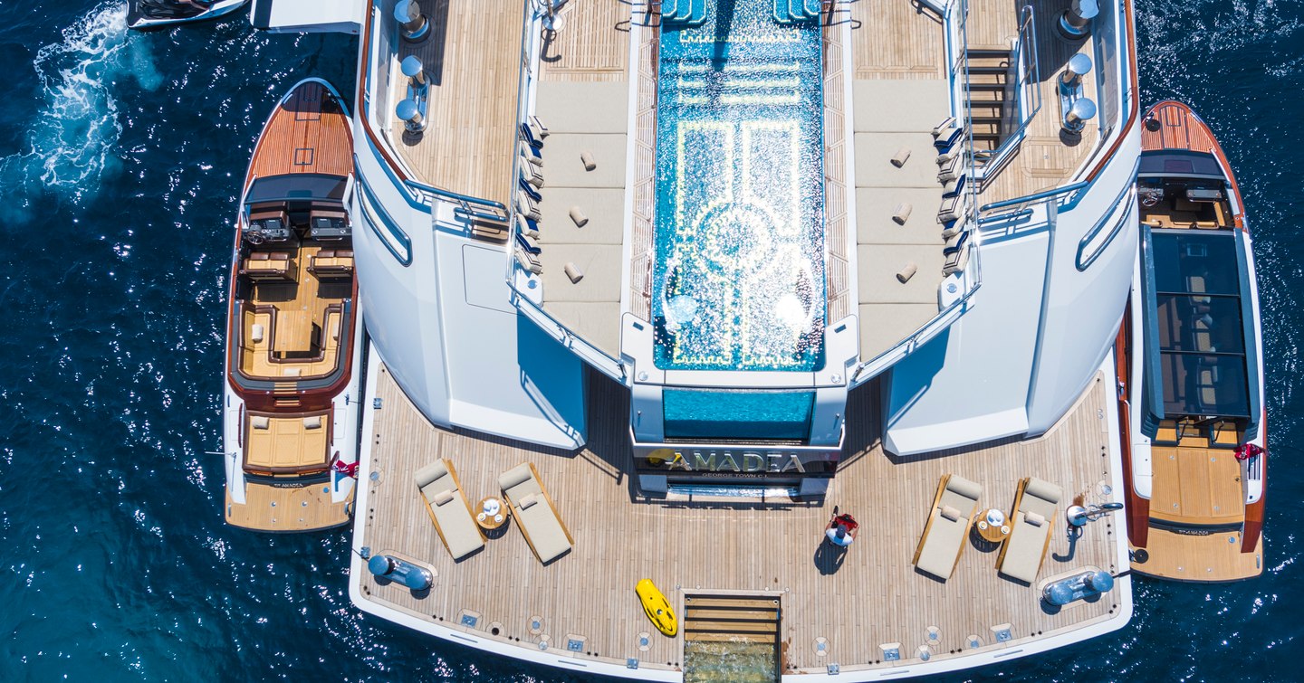 Aerial shot of aft deck on board superyacht Amadea with infinity pool and tenders