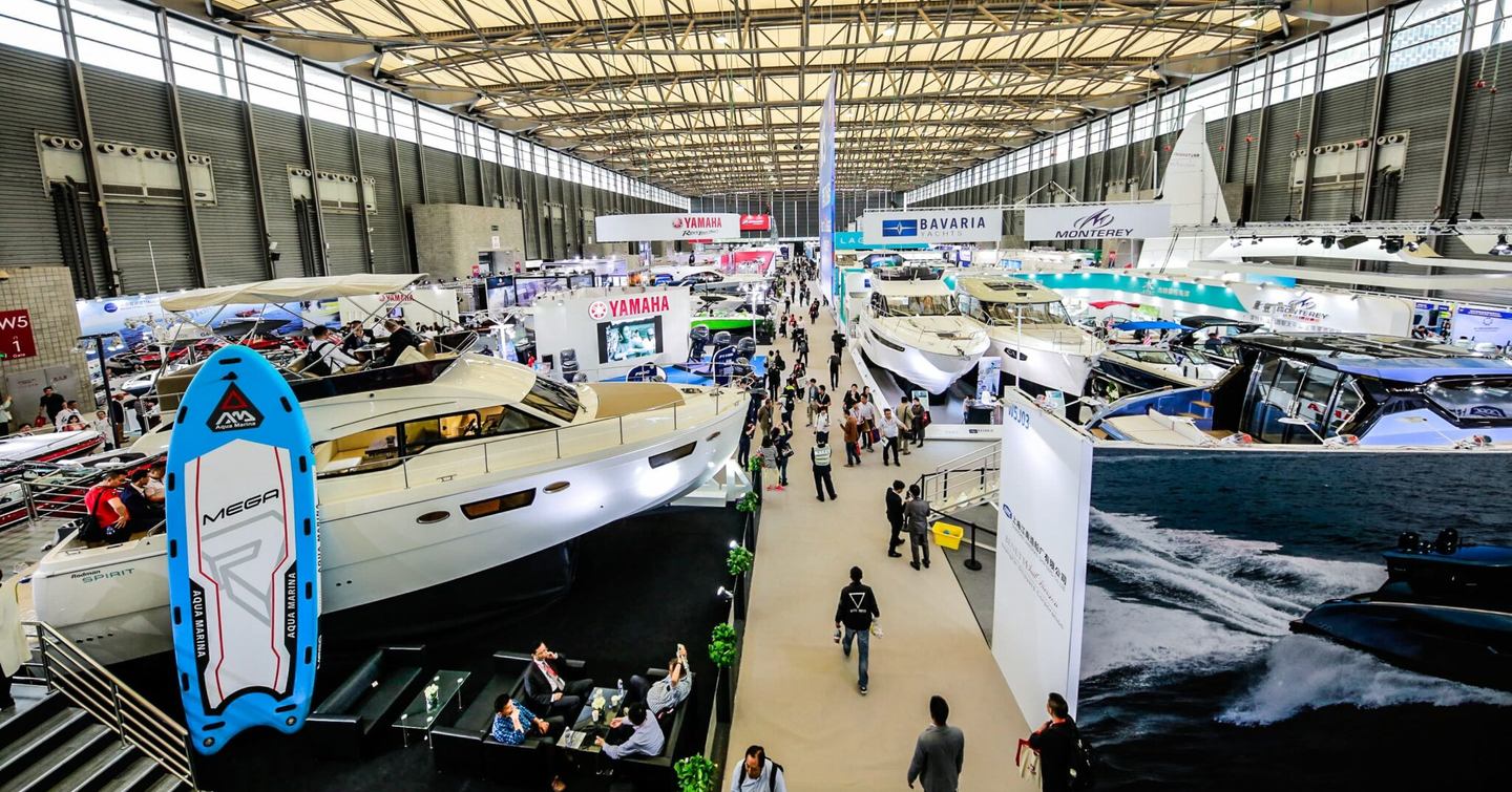 Crowds walking through hall full of yachts