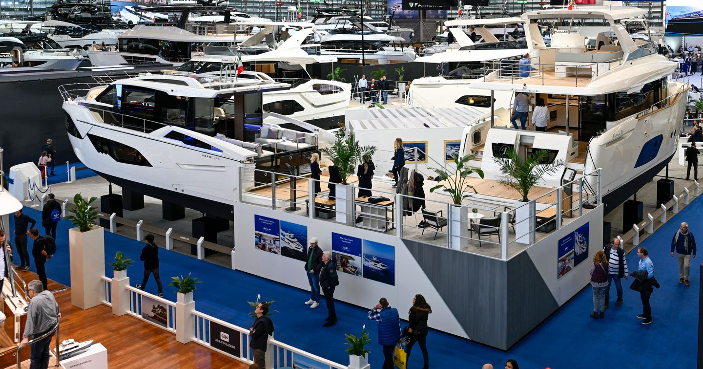 Overview of a hall at boot Düsseldorf with yachts on display and visitors walking around