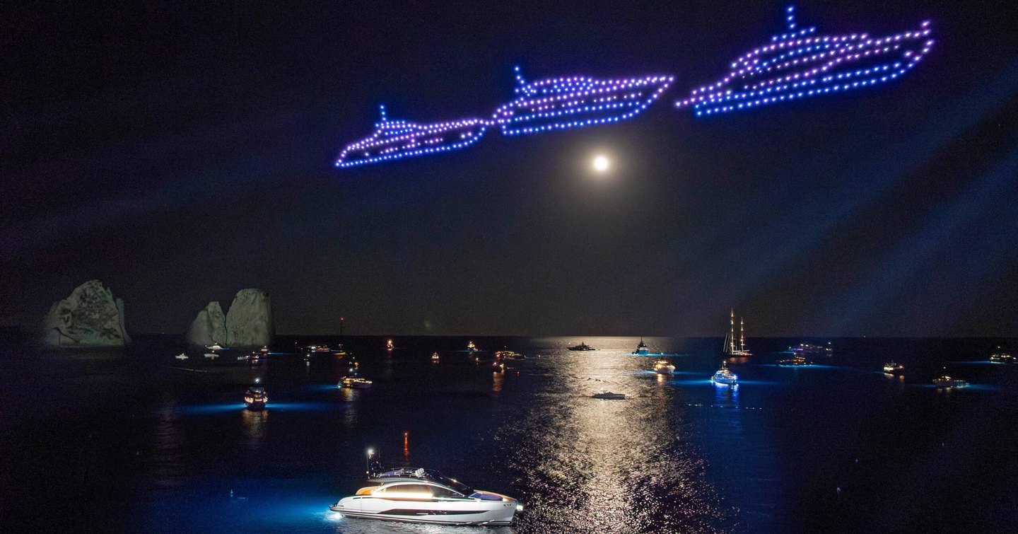 Pershing GTX70 motor yacht at night with drone light show