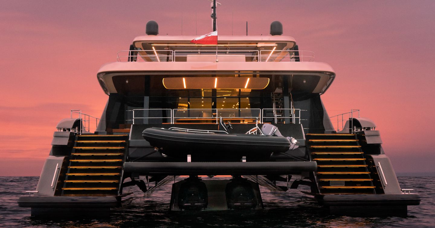 100 Sunreef Power night time shot taken from water level towards the aft deck, tender on deck, red sky in background