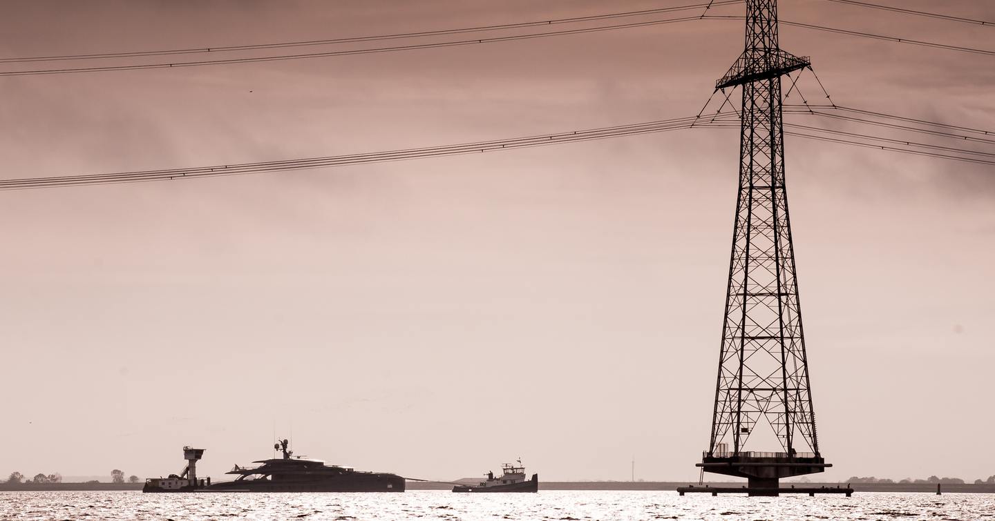 Superyacht PHI silhouetted on sea with mast in foreground