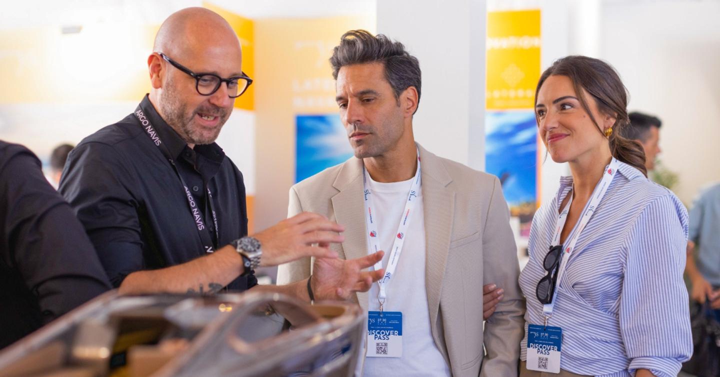 A man at the mys 2024 yacht innovation hub explains a product to a man and a woman