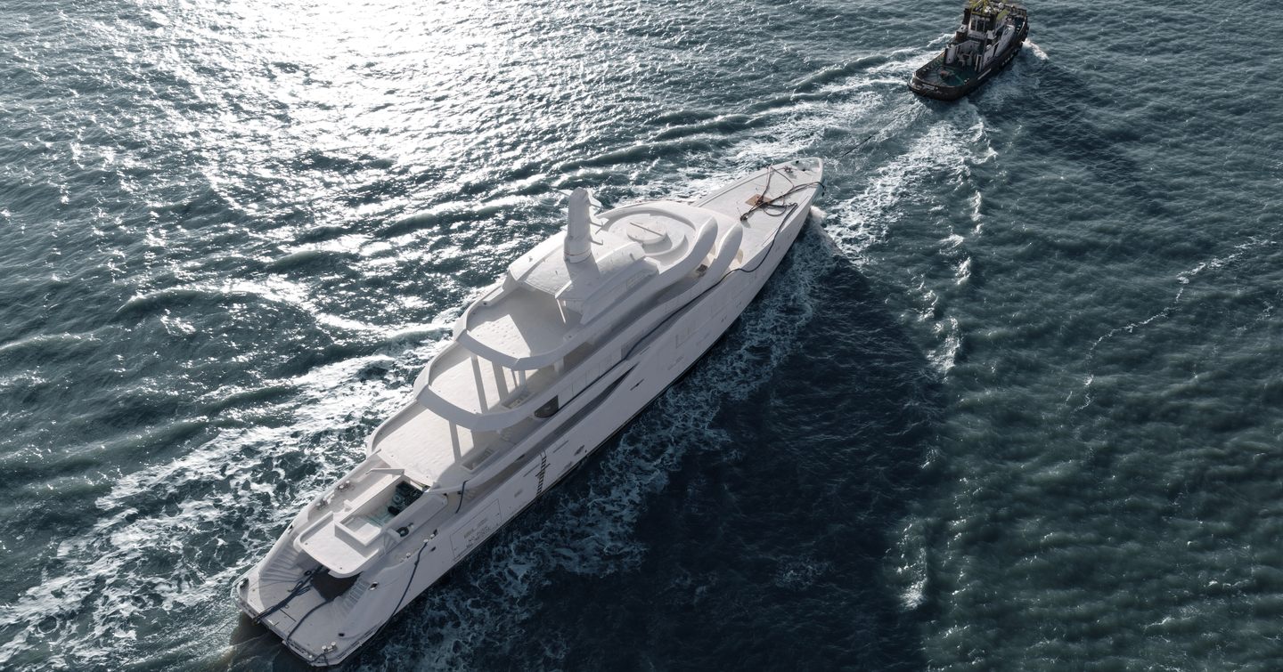 Aerial view of Fifth Amels 80 superyacht pre-outfitting behind tugbaot 
