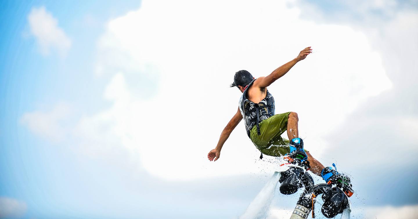 Male demonstrator on flyboard, surrounded by clouded sky.