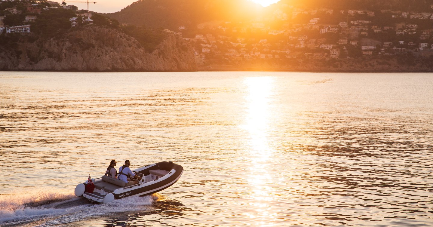 Williams Jet Tender moving at speed on water at sunset with hills in background