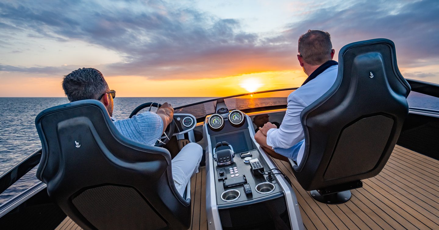 Two men sat at helm console as sunsets