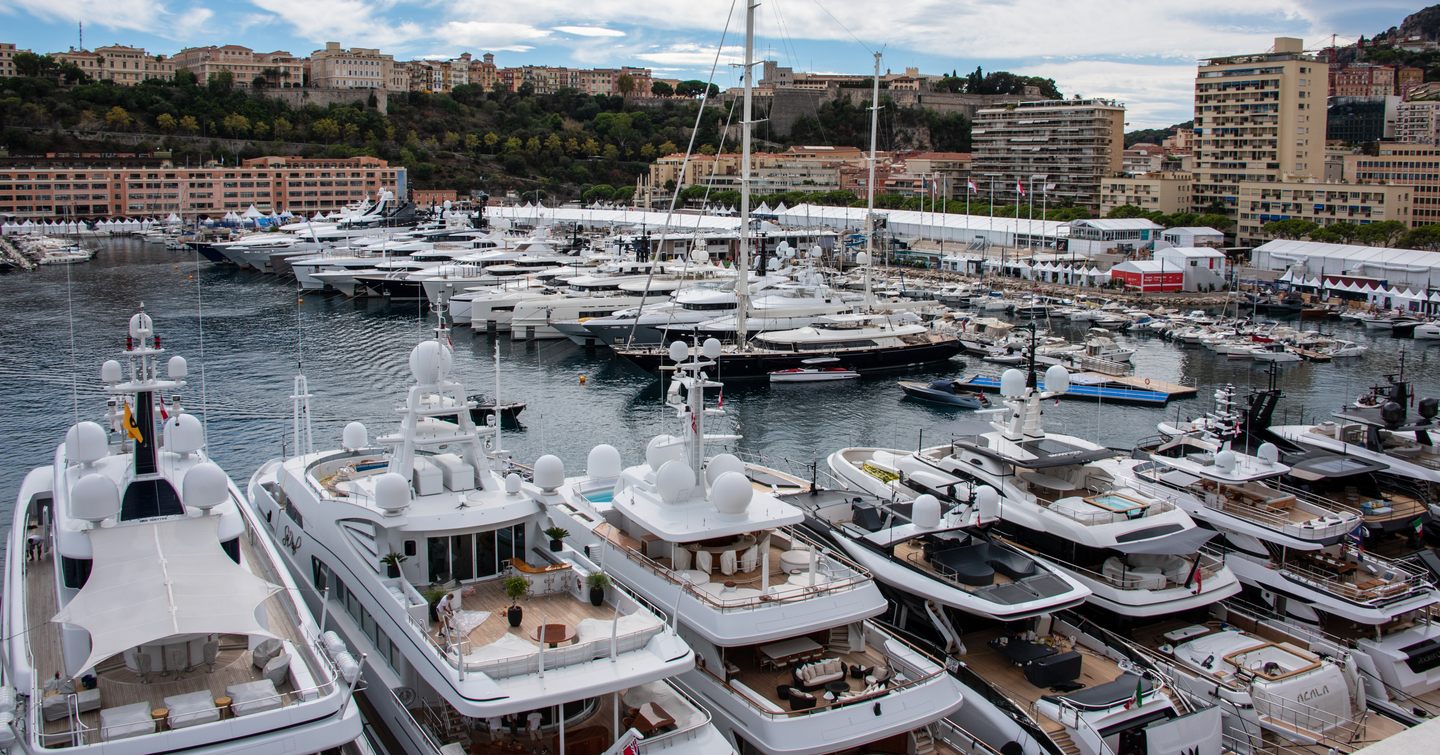 Aft view of superyachts berthed in a line along the dock at the Monaco Yacht Show.