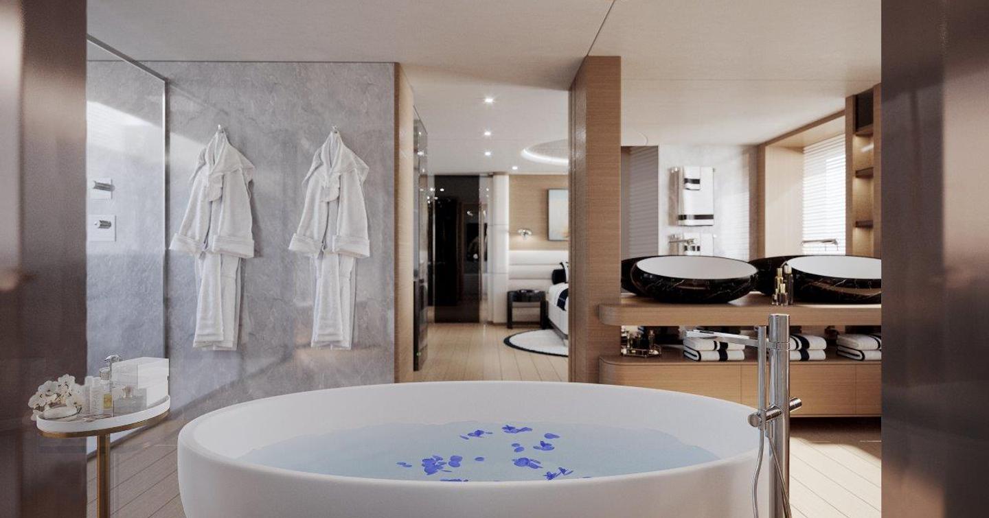 Bath in open plan bathroom in bedroom with dressing gowns hanging on wall