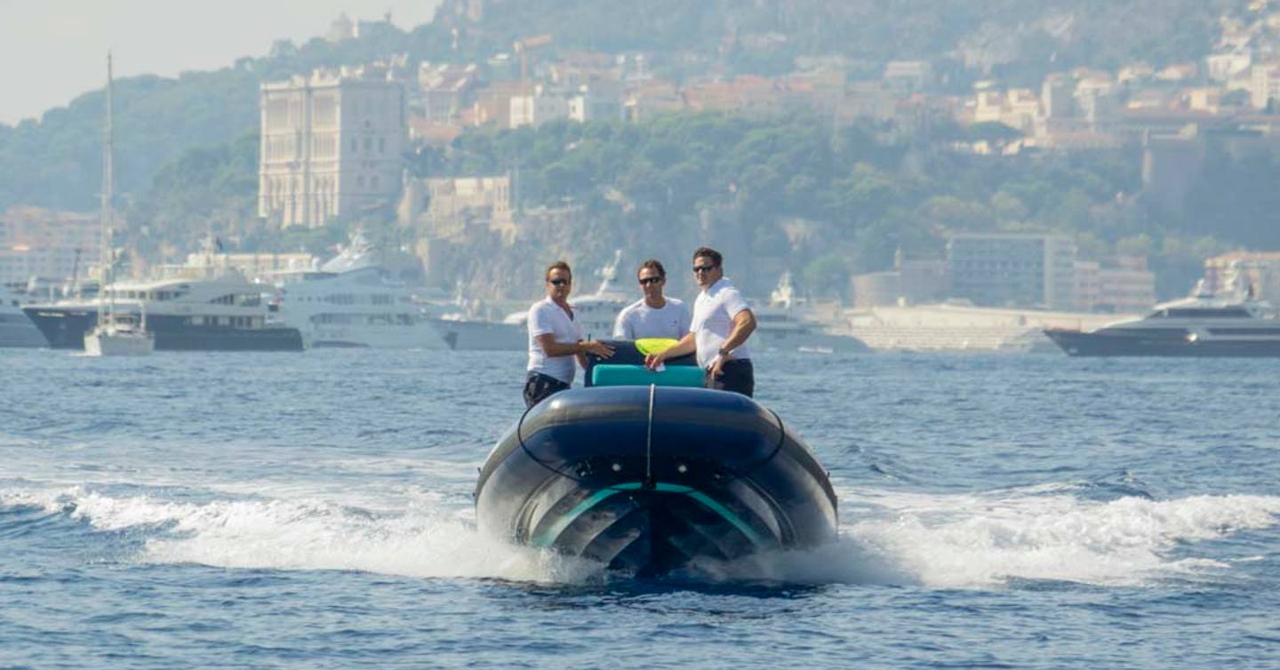 Three males on SOLAS tender with rugged coast in background