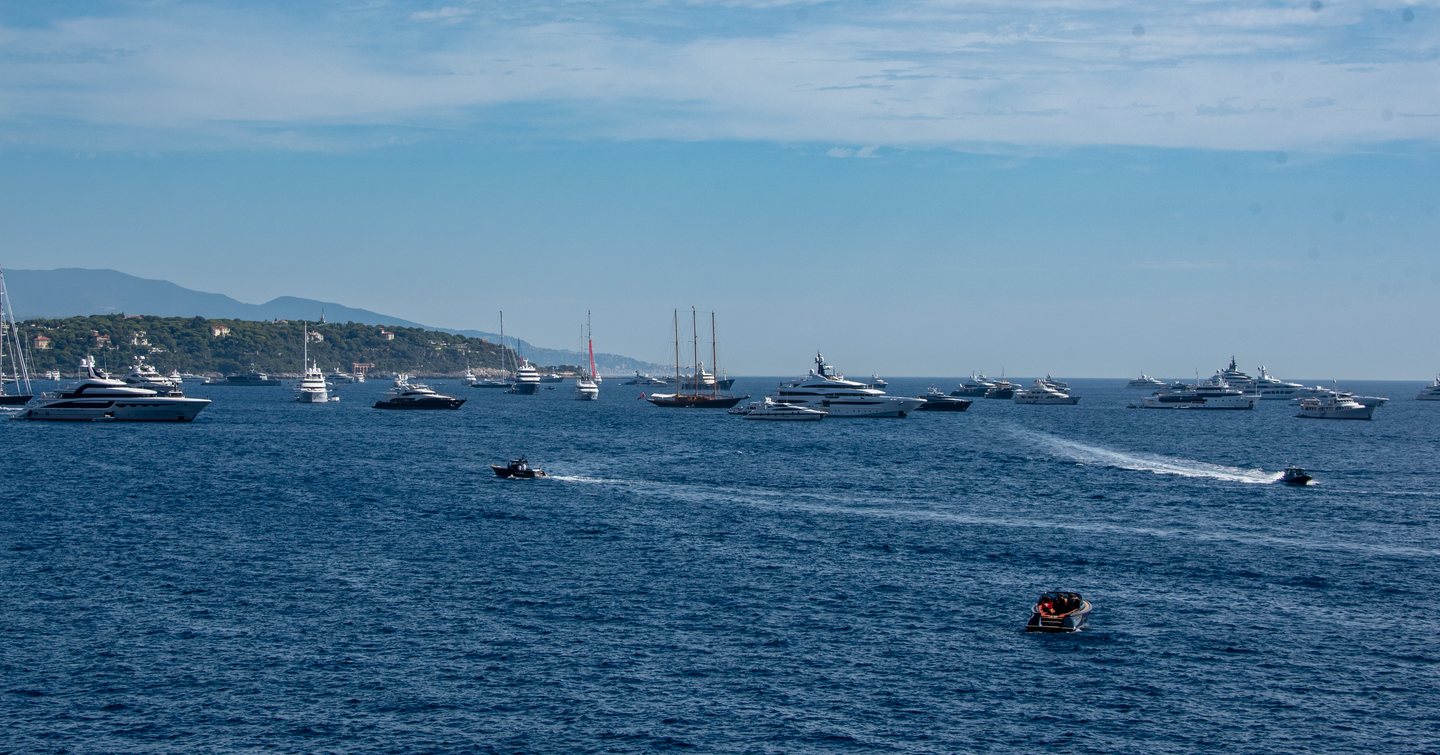 images shows yachts on anchor in the distance at Monaco Yacht Show 2023, luxury tenders in the foreground carrying passengers and yacht buyers to and from the yachts on anchor