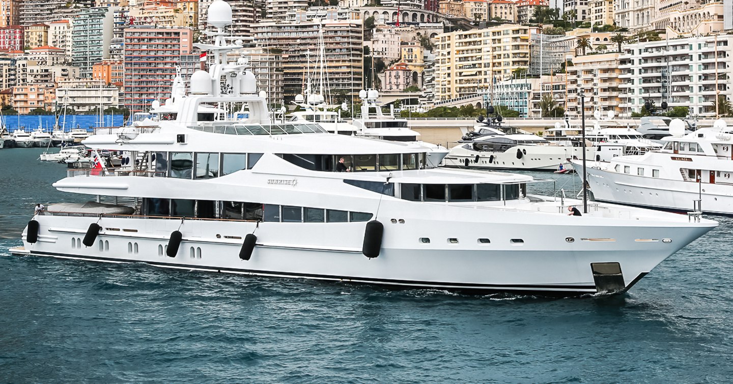 Oceanco yacht FRIENDSHIP shown making way slowly in marina setting, the yacht has fenders on starboard side, land in background