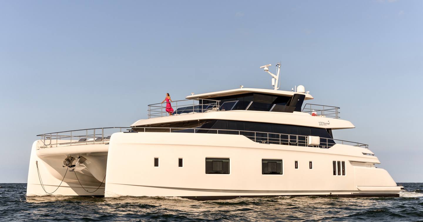 Sunreef 100 Power THEA IV shown from water level towards port bow and side profile, yacht still in calm waters on a bright day