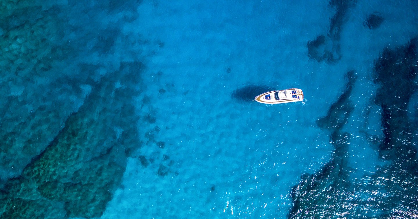 Aerial view of tropical island beach holiday yacht on blue reef ocean