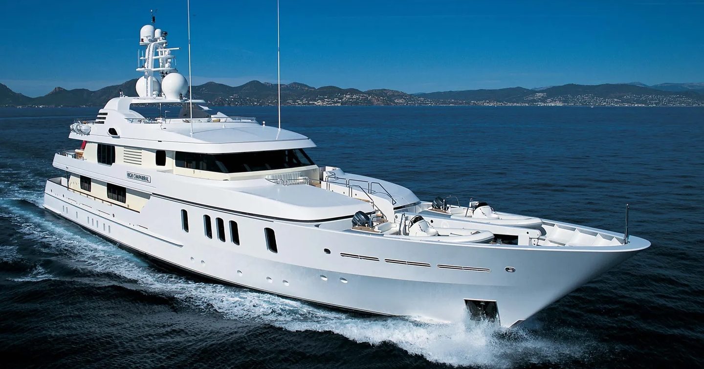 Feadship yacht ADVENTURE is a charter yacht shown in the image running in calm waters on a bright day, land in distant background; shot is mid aerial ahead of the starboard bow