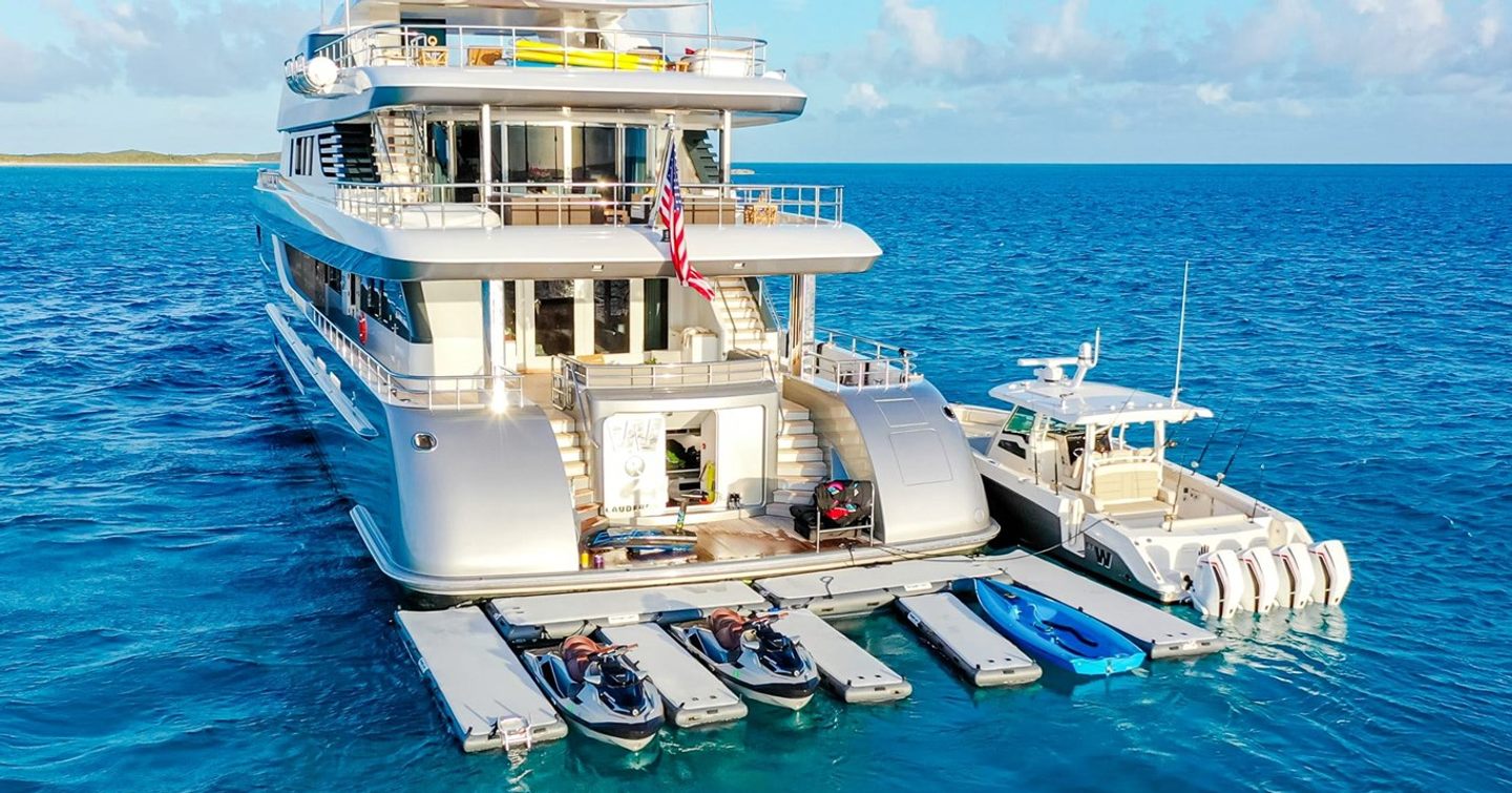 Motor yacht W's aft deck beachclub with floating docks, jet skis, and a tender alongside the swim platform 