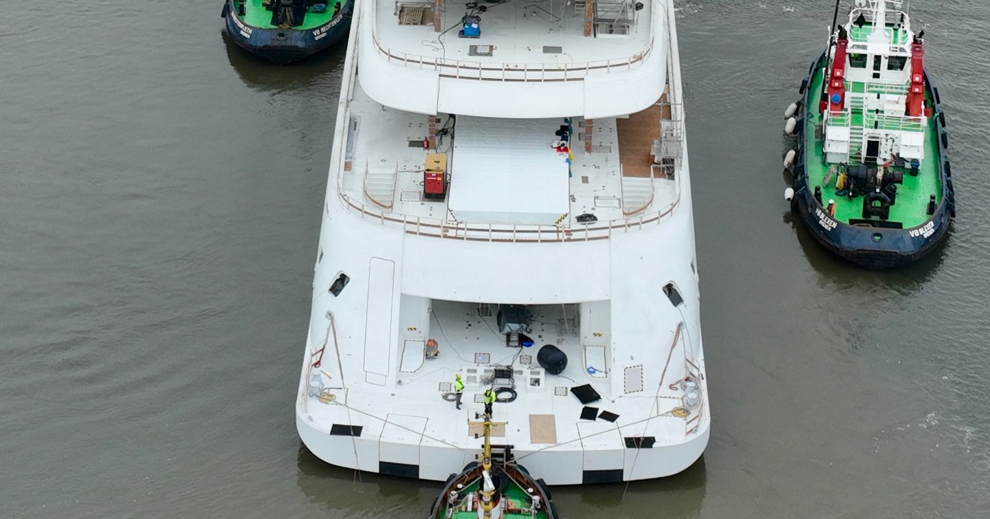 Aerial view of Superyacht Project Defy's aft decks surrounded by tugboats