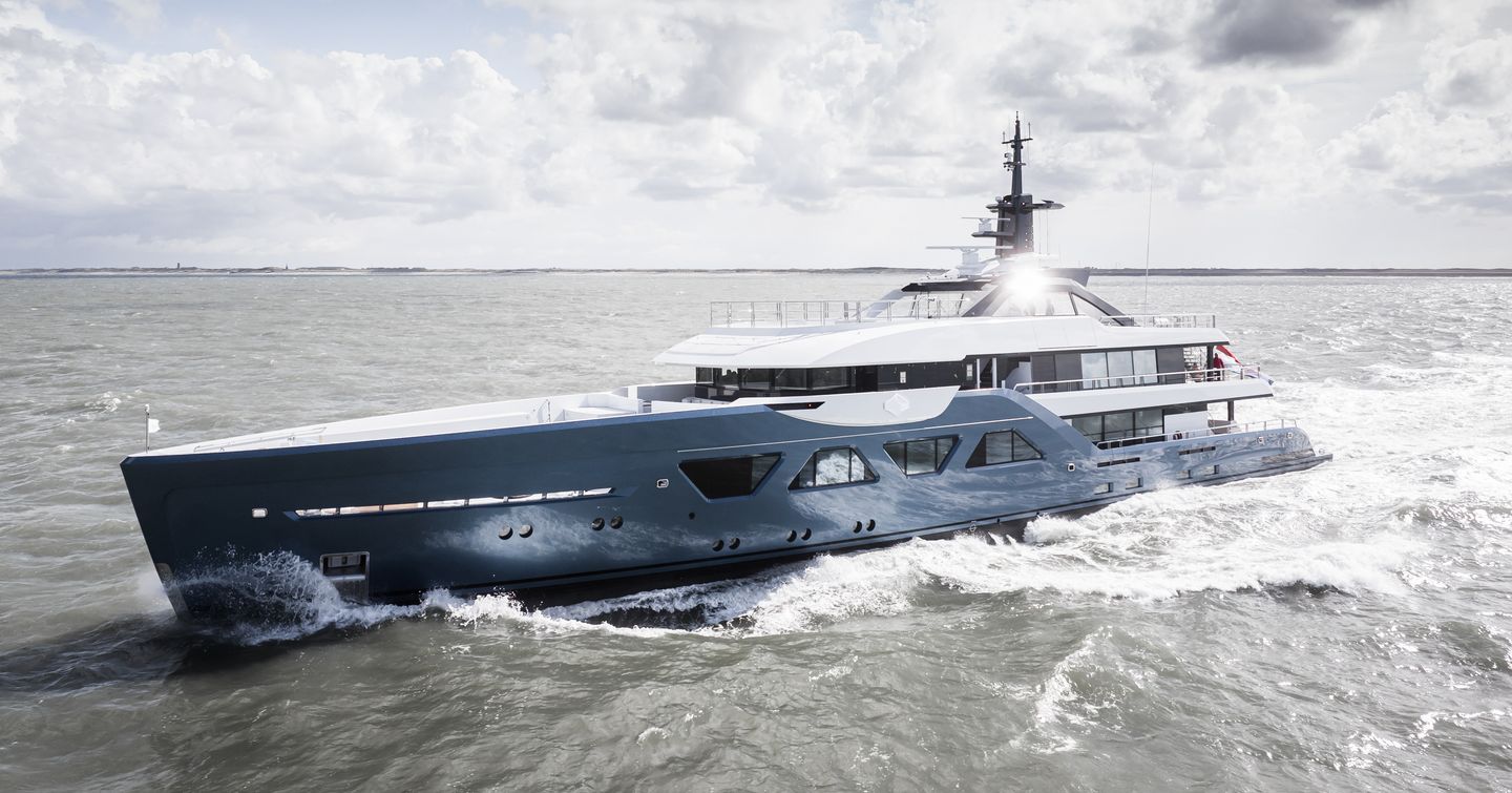 Superyacht Amels 60 on sea trials in calm sea, cloudy day, seen from mid aerial shot over port bow and along side profile